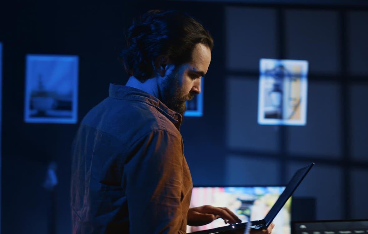 IT engineer working on a laptop in a dimly lit office